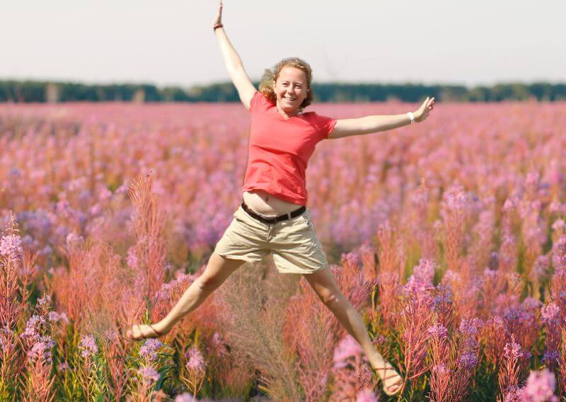 Anne Thevenon qui représente la femme sautant de joie dans un champ de fleurs, symbolisant la liberté et l’harmonie retrouvées avec son cycle.